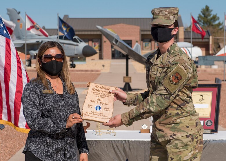Senior Airman Ayla Squires, right, Airman Leadership School graduate, accepts the academic achievement award during the graduation of ALS class 21-1, Nov. 5, 2020, on Holloman Air Force Base, New Mexico. The academic award is presented to the student with the highest overall average on all academic evaluations. (U.S. Air Force photo by Staff Sgt. Christine Groening)
