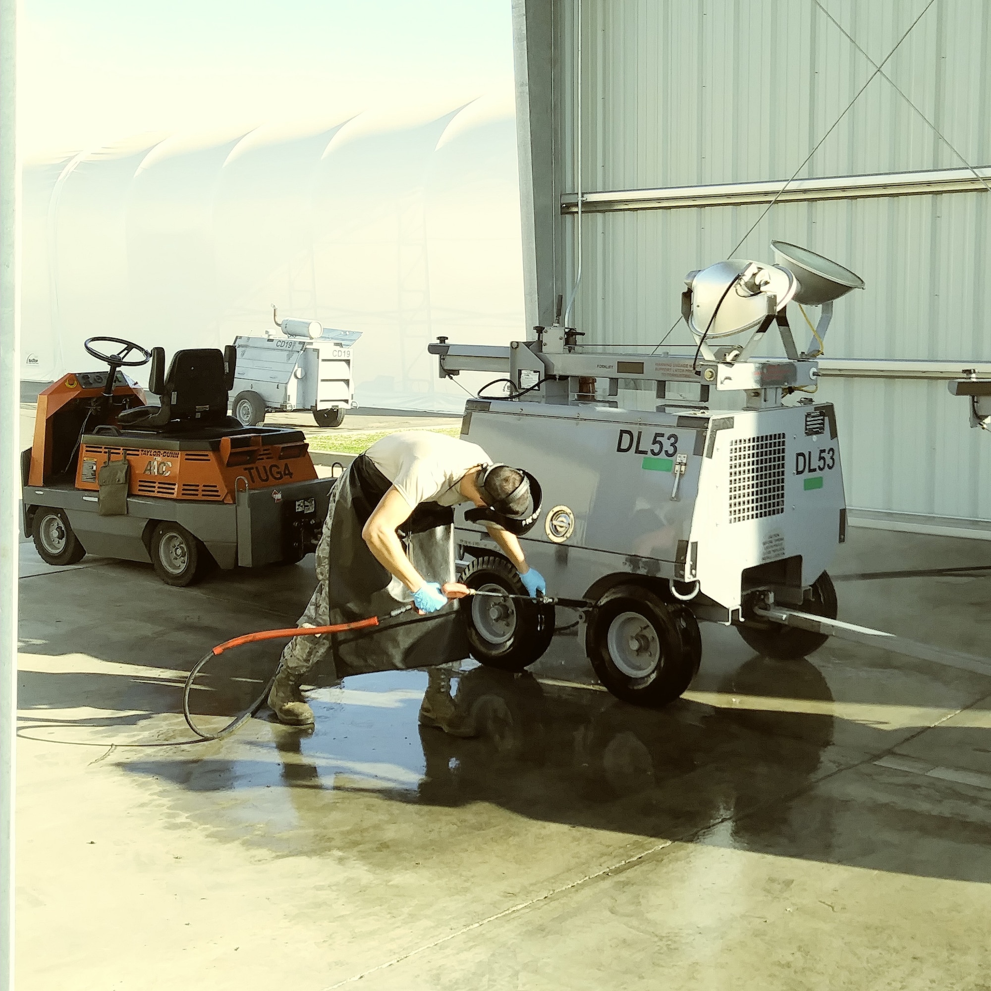 An AGE maintenance crew member uses the new wash rack to clean residue from flight line equipment.