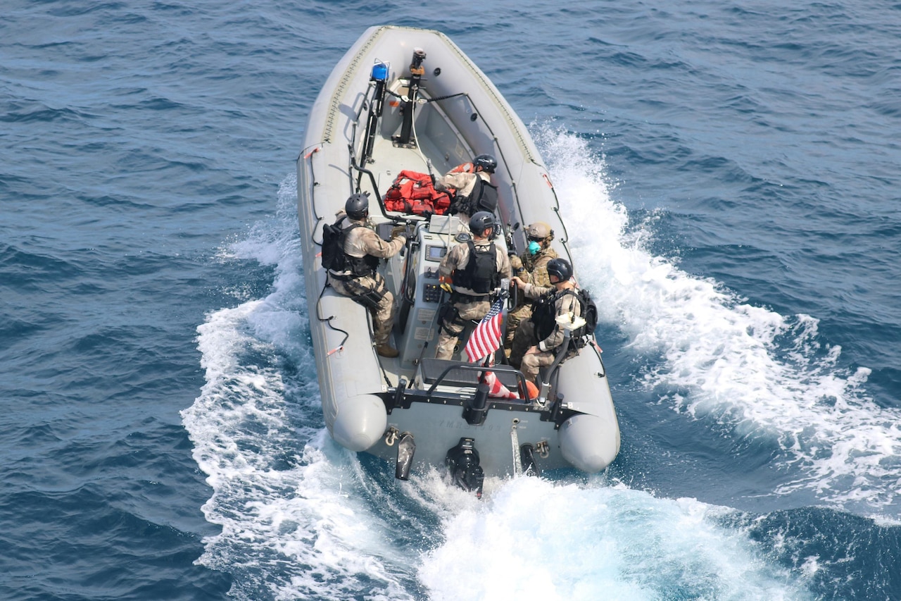 Military members ride aboard a small boat.