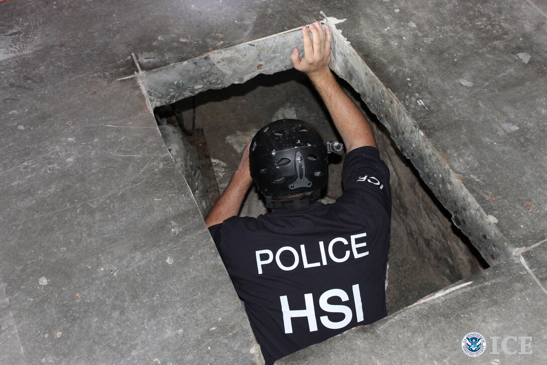 A person in a police uniform climbs into a tunnel.