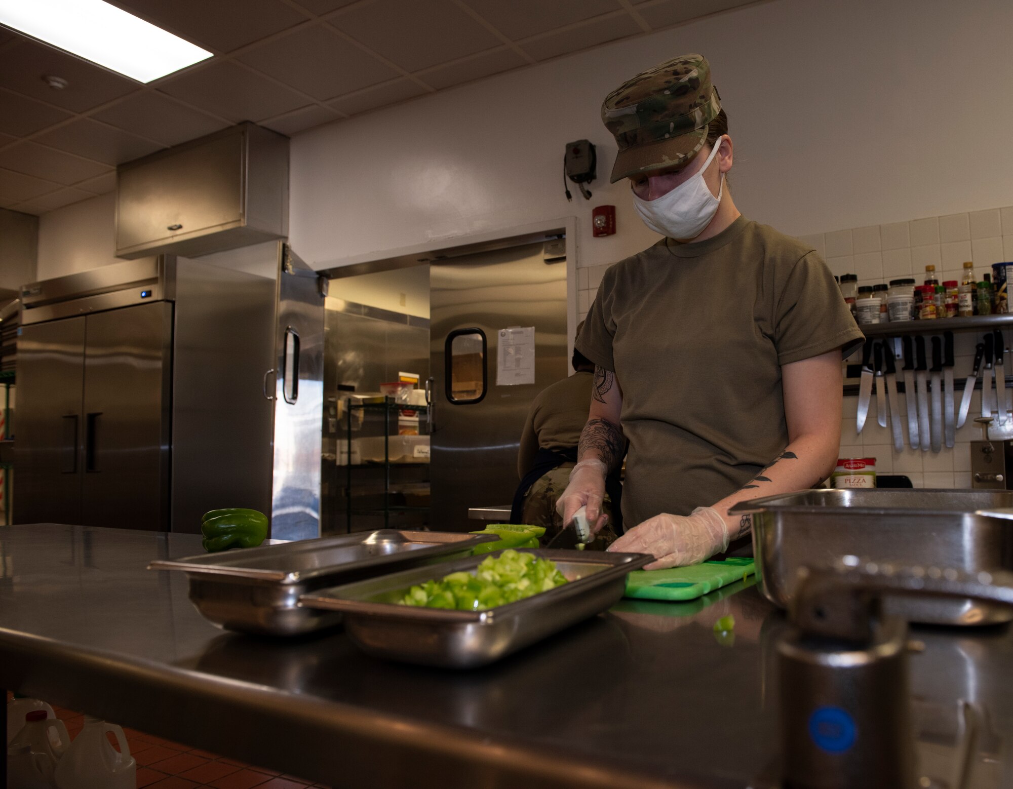 An Airman chops green peppers in the dining facility kitchen.