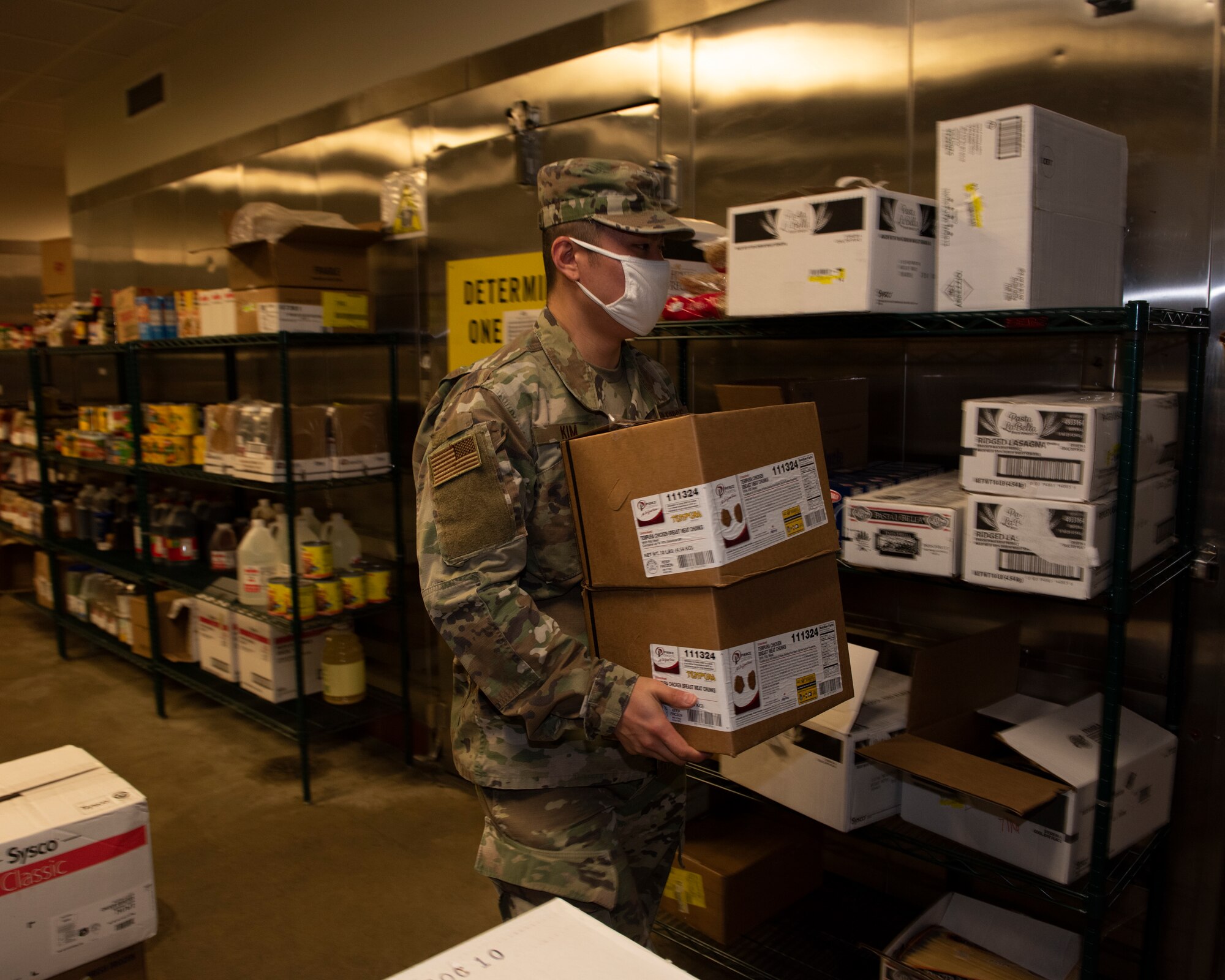 An Airman picks up a couple a boxes of food to storage.
