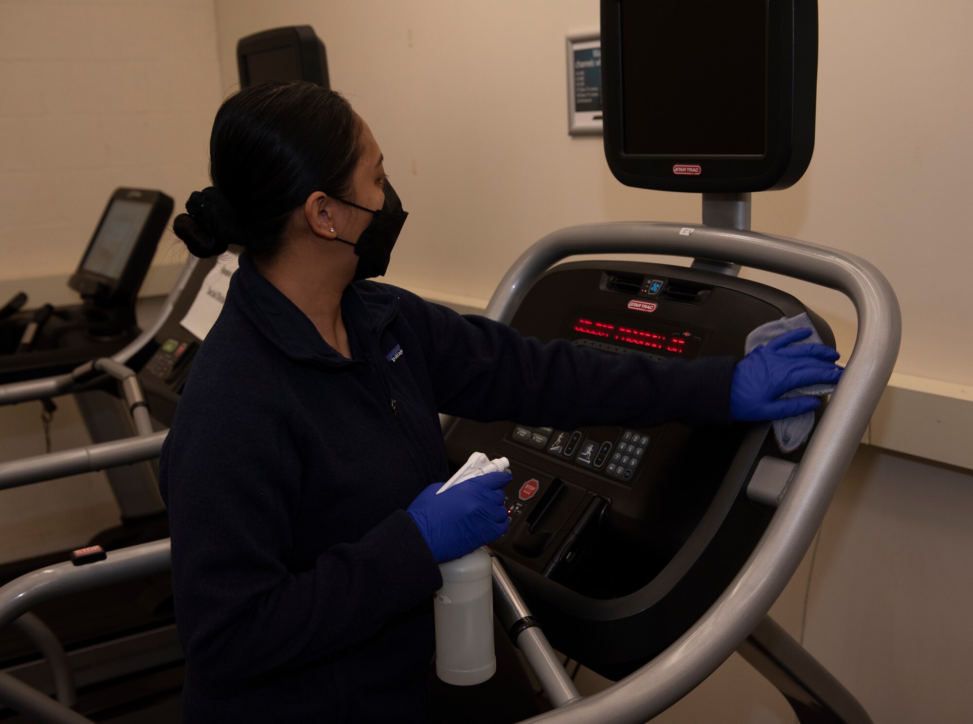 An Airman cleans a treadmill inside the main gym.