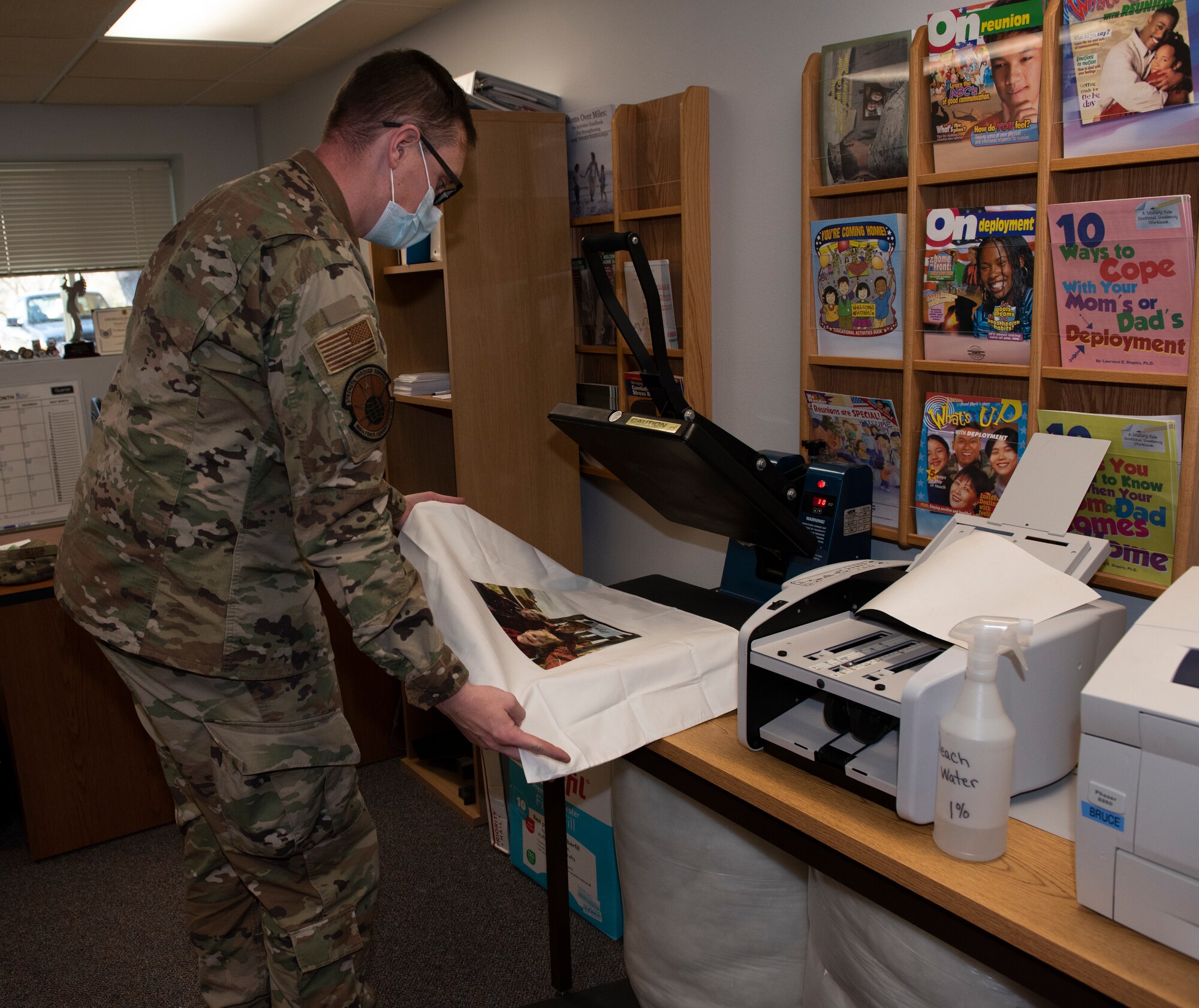 A sergeant picks up a pillow case that has a family picture placed on the pillow.