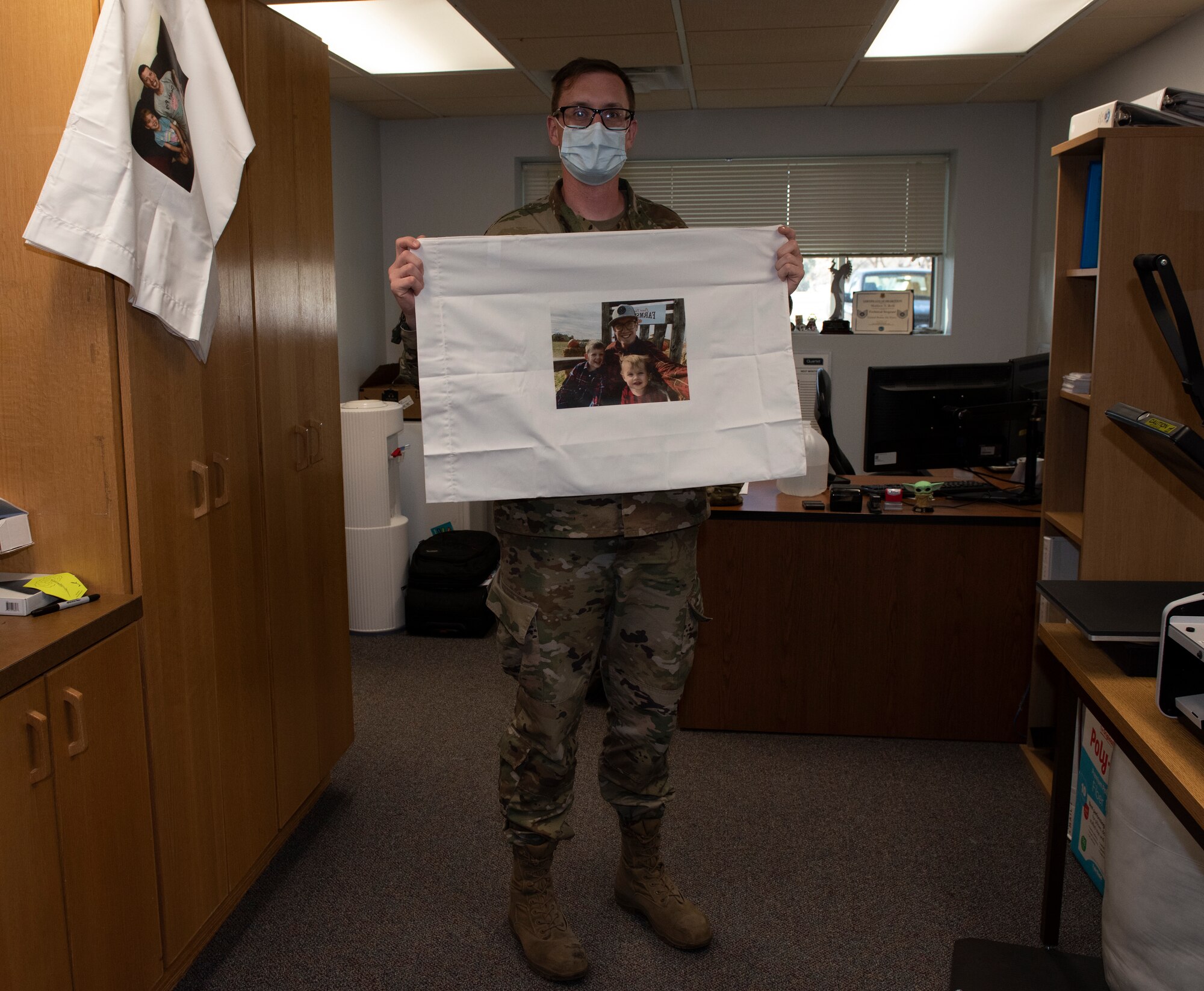 A sergeant picks up a pillow case that has a family picture placed on the pillow.