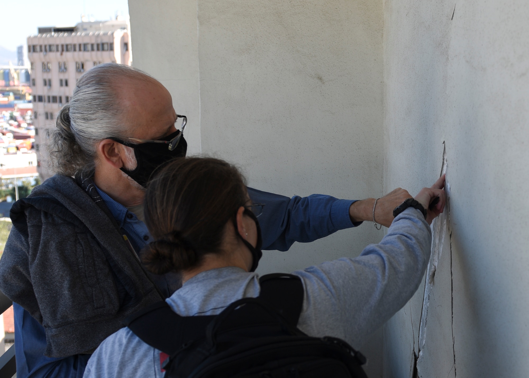 Two people pointing at a cracked wall