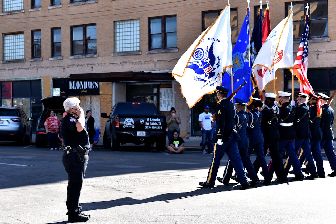 San Angelo Police officer salutes the flag as the Goodfellow Joint Service Color Guard passes during the Veterans Day Parade in downtown San Angelo, Texas, Nov. 7, 2020. The parade had over 70 float entries. (U.S. Air Force photo by Staff Sgt. Seraiah Wolf)