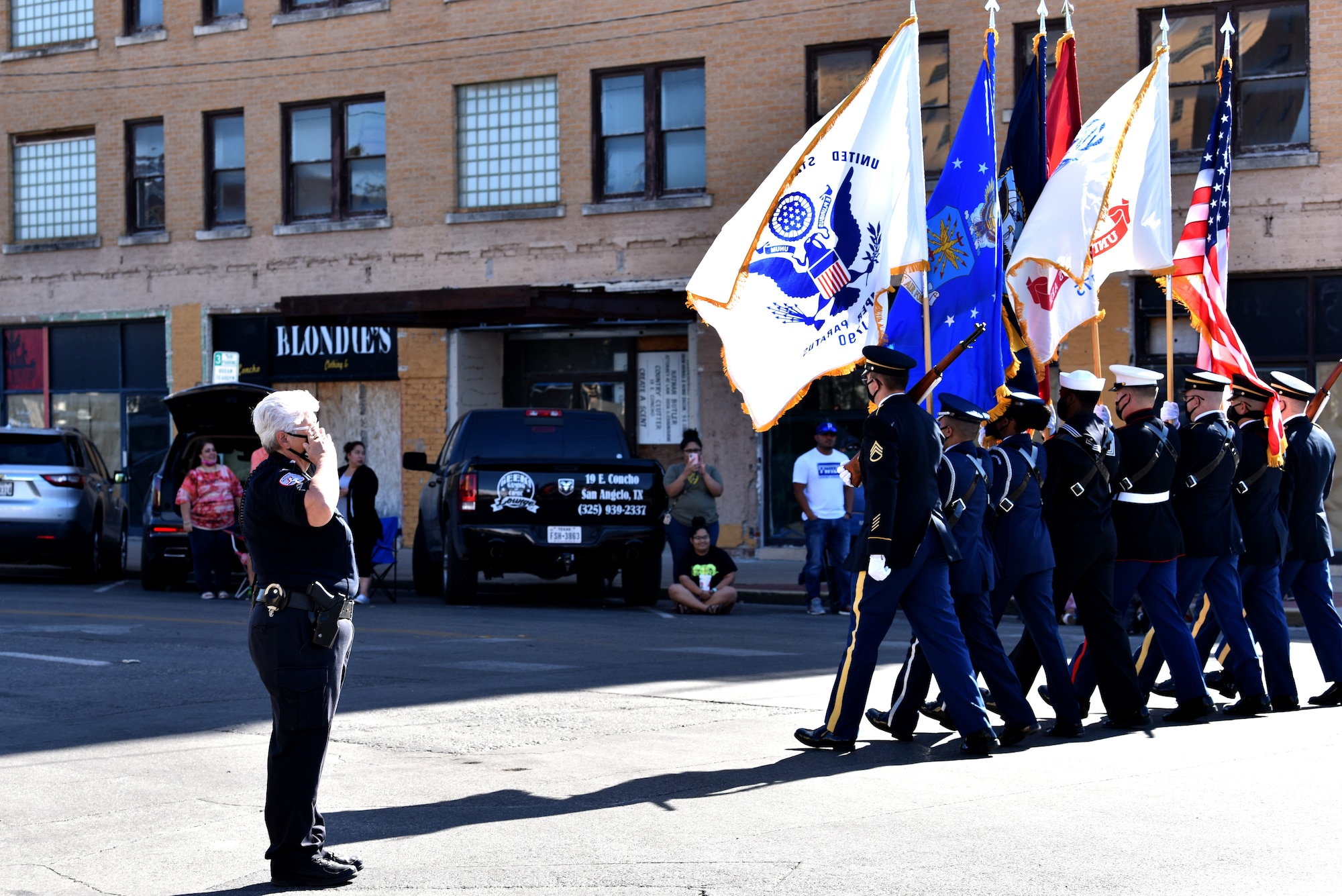 San Angelo Police officer salutes the flag as the Goodfellow Joint Service Color Guard passes during the Veterans Day Parade in downtown San Angelo, Texas, Nov. 7, 2020. The parade had over 70 float entries. (U.S. Air Force photo by Staff Sgt. Seraiah Wolf)