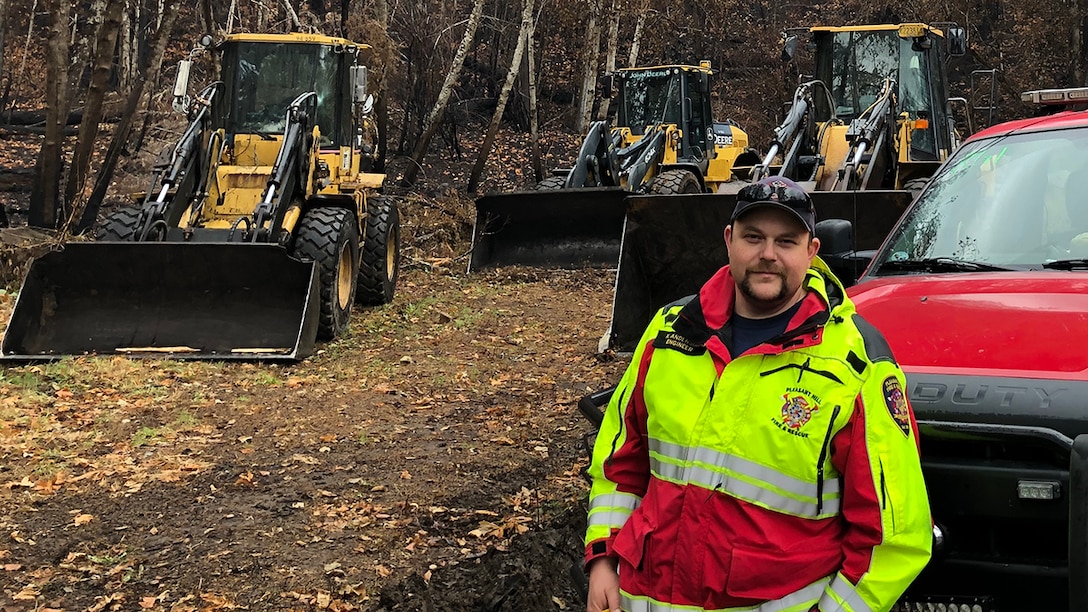 Kyle Anderson stands in front of equipment used to clear debris from highways and side roads caused by the Holiday Farm wildfire.