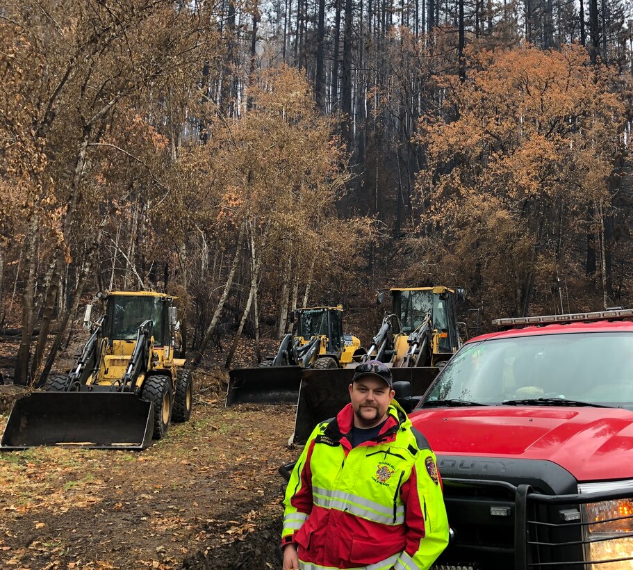 Kyle Anderson stands in front of equipment used to clear debris from highways and side roads caused by the Holiday Farm wildfire.