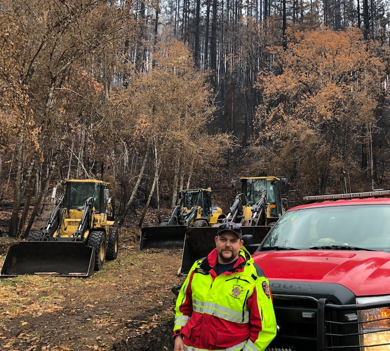 Kyle Anderson stands in front of equipment used to clear debris from highways and side roads caused by the Holiday Farm wildfire.