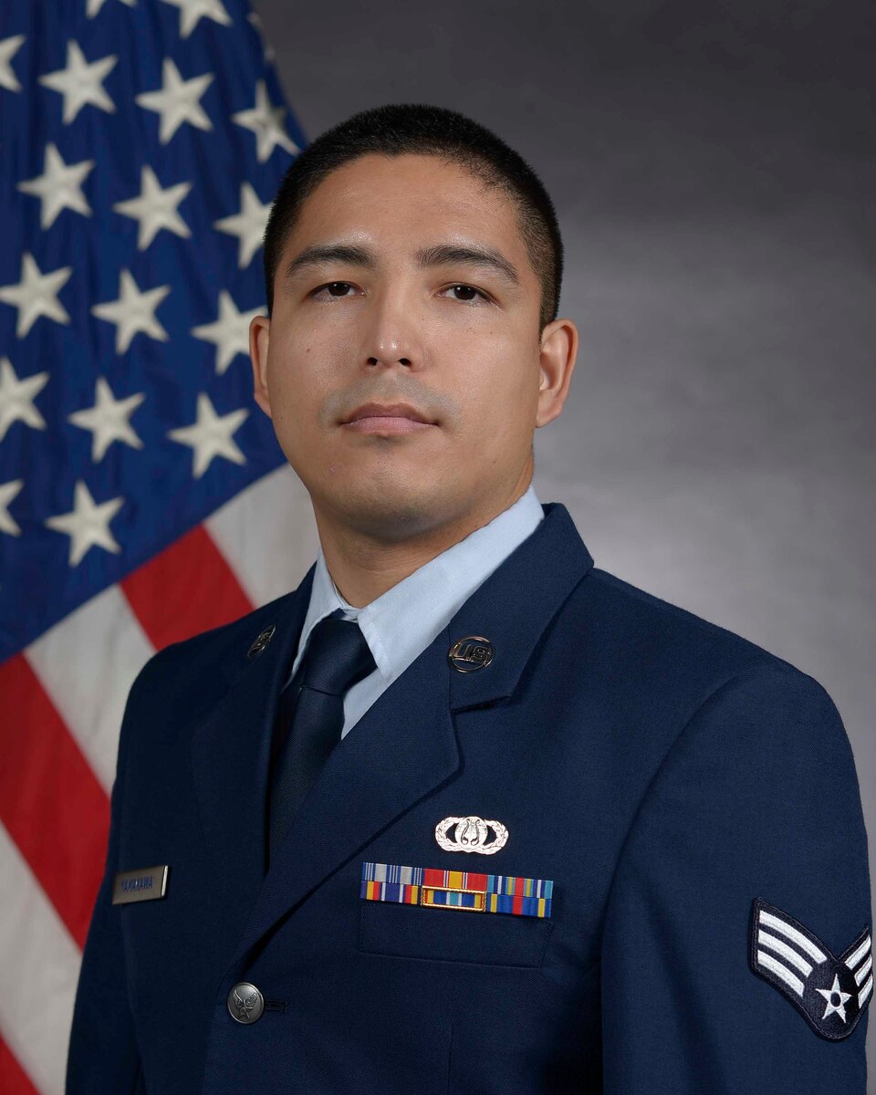 An Airman in uniform in front of the United States flag.