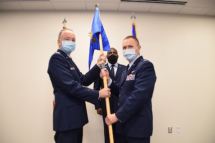 Col. Michael C. Brice, 433rd Medical Group commander, presents the 433rd Aeromedical Staging Squadron unit guidon to Col. David P. Bailey during an assumption of command ceremony Nov. 7, 2020 at Joint Base San Antonio-Lackland, Texas. The ceremony was held at the 433rd Medical Group building. (U.S. Air Force photo by Tech. Sgt. Iram Carmona)