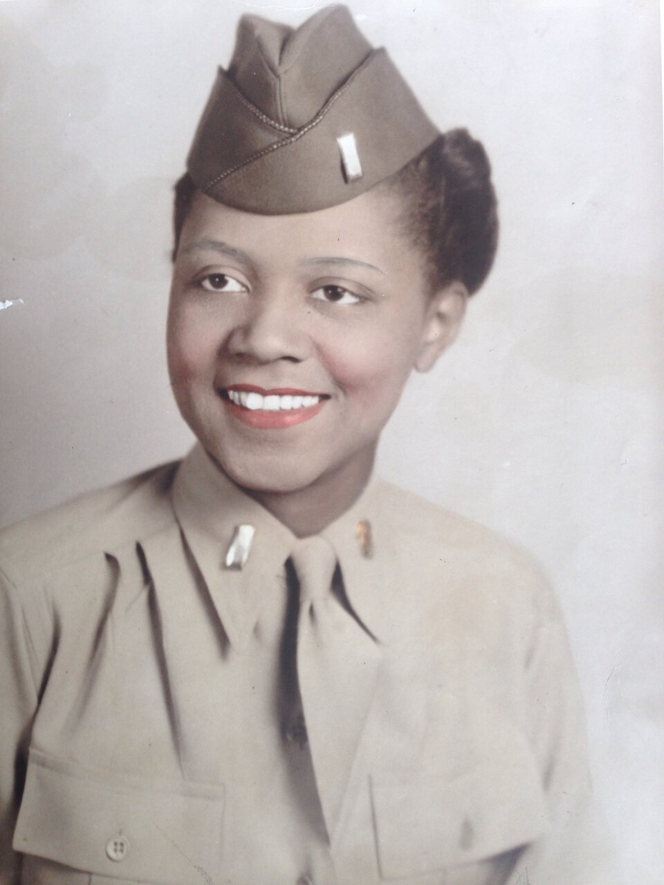 A woman in cap and uniform smiles.
