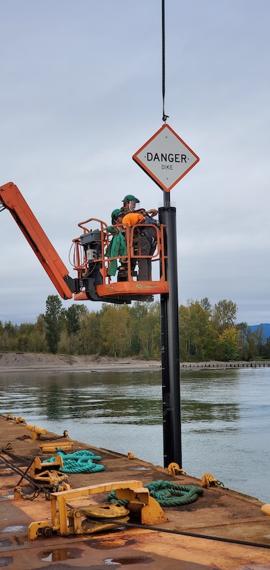 Workers installing a king pile marker warning sign