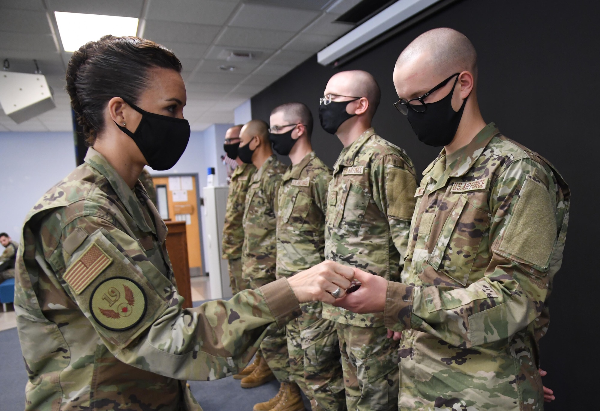 U.S. Air Force Chief Master Sgt. Kristina Rogers, Nineteenth Air Force command chief, Joint Base San Antonio-Randolph, Texas, presents a coin to Airman David McCoy, basic military training graduate, following the final BMT graduation ceremony inside the Levitow Training Support Facility at Keesler Air Force Base, Mississippi, Nov. 6, 2020. Nearly 60 trainees from the 37th Training Wing Detachment 5 completed the six-week BMT course. Throughout the duration of BMT training at Keesler, 18 flights and 939 Airmen graduated. (U.S. Air Force photo by Kemberly Groue)