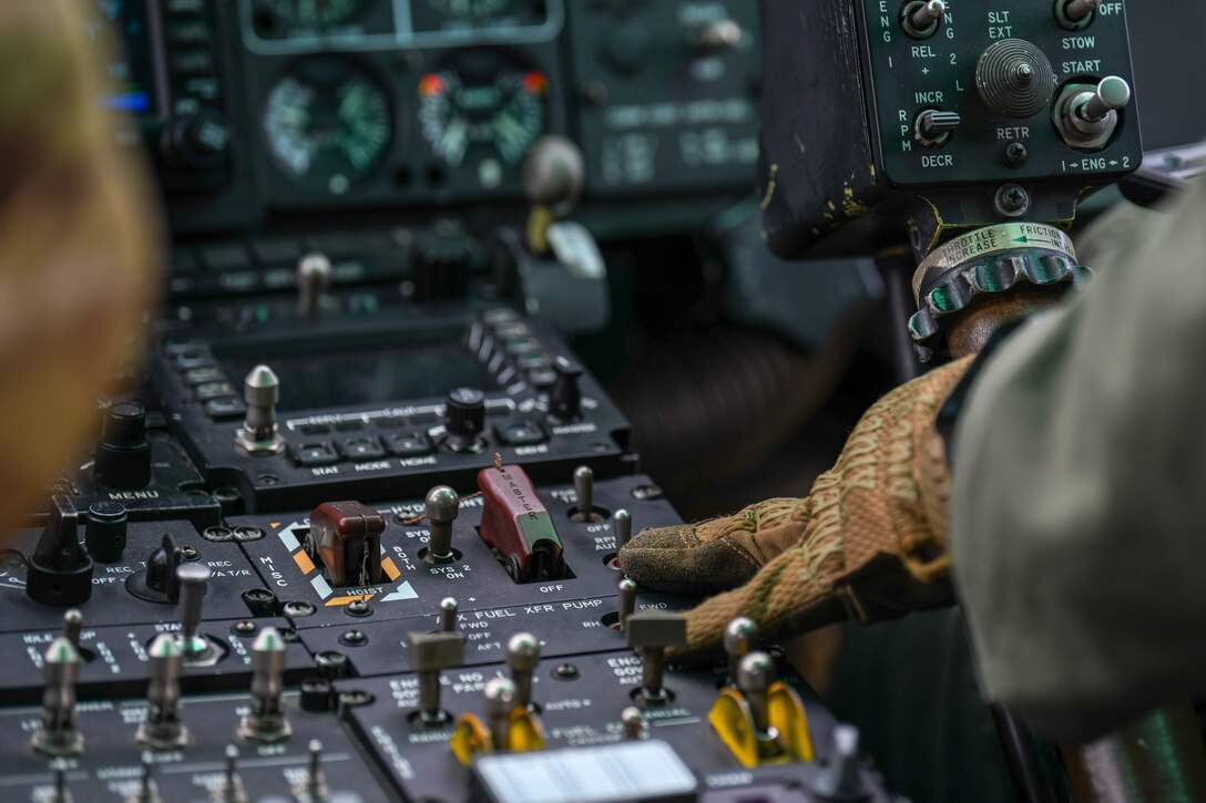 Pilot adjusts UH-1N Iroquois helicopter controls while flying.