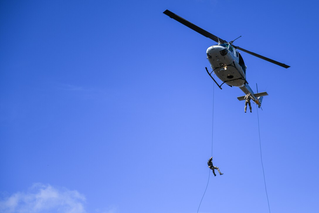 Operators rappel from UH-1N Iroquois helicopter.