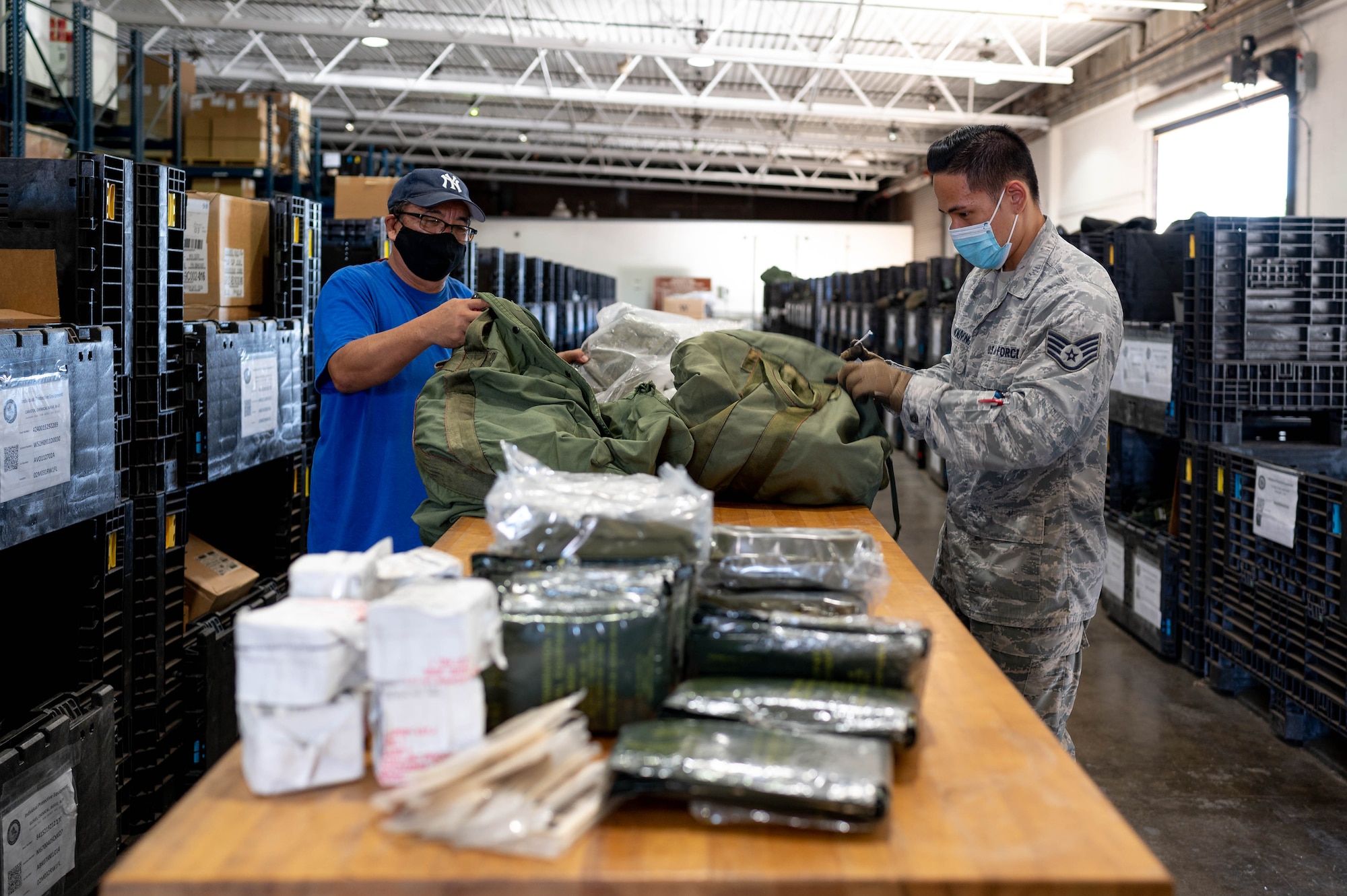 201105-N-TA290-1001 HONOLULU (November 5, 2020) Naval Supply Systems Command Fleet Logistics Center Pearl Harbor, material handler, Joe Rivera (left) and 647th LRS staff sergeant Chuck Phanouvang prepares C-bags (chemical protective equipment) in support of the 647th Logistics Readiness Squadron participation in the 15th Wing's annual Tropic Tempest exercise.(U.S. Navy photo by Daniel Mayberry/Released)