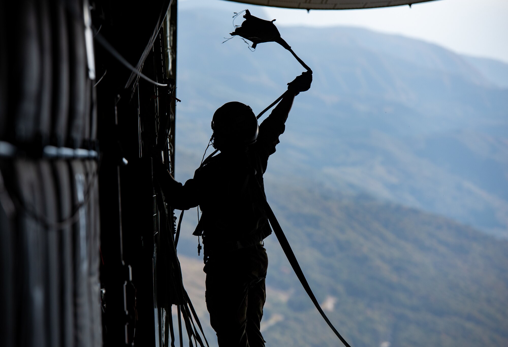 Staff Sgt. Vincenzo Gallegos, 36th Airlift Squadron loadmaster, retrieves a parachute line during a cargo drop during Keen Sword 21