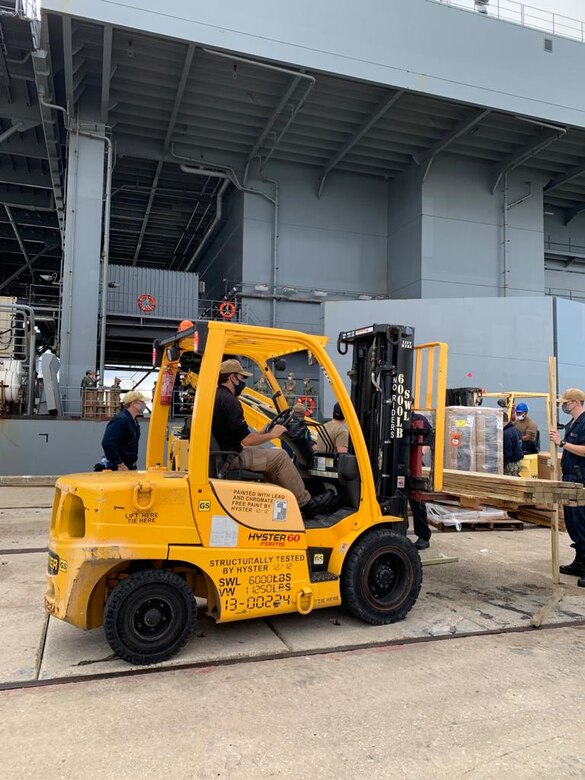 Lt. Joshua Cabral (left), USS Hershel “Woody” Williams’ supply officer, monitors the operation of a MULAG Conveyor Belt used by the Naval Supply Systems Command Logistics Support Center (NAVSUP LSC) team during USS Hershel “Woody” Williams’ (ESB 4) port visit Oct. 22, 2020 at Naval Station Rota, Spain. The LSC team comprises logistics professionals who are U.S. and Spanish national civilians and U.S. military members.