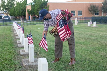 Norfolk Naval Shipyard (NNSY) Veteran Employee Readiness Group (VET-ERG) Founding Member Jonathan Echols placing flags at the gravestones of fallen service members at the Captain Ted Conaway Memorial Naval Cemetery in Naval Medical Center Portsmouth (NMCP) in honor of Veterans Day.