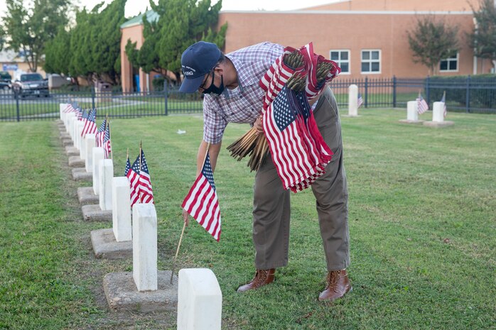 Norfolk Naval Shipyard (NNSY) Veteran Employee Readiness Group (VET-ERG) Founding Member Jonathan Echols placing flags at the gravestones of fallen service members at the Captain Ted Conaway Memorial Naval Cemetery in Naval Medical Center Portsmouth (NMCP) in honor of Veterans Day.