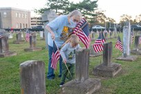 Members of the Navy Wives Club of America (NWCA) Portsmouth 221 help place flags at the gravestones of fallen service members at the Captain Ted Conaway Memorial Naval Cemetery in Naval Medical Center Portsmouth (NMCP) in honor of Veterans Day.