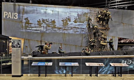 Three New York Army National Guard Soldiers posed for figures in this exhibit at the National Museum of the United States Army of a Higgins boat landing in Normandy on D-Day, June 6, 1944. Maj. Kevin Vilardo was the model for the photographer in the stern, while 1st Lt. Sam Gerdt modeled the Soldier waiting at the side of the boat. Sgt. 1st Class Nick Archibald was the model for one of the Soldiers climbing down the cargo net. The museum opens to the public Nov. 11, 2020.