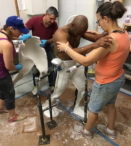 Technicians help New York Army National Guard Sgt. 1st Class Jonathan Morrison hold his pose as they remove a cast of his lower torso at Studio EIS in Brooklyn, N.Y., Nov. 5, 2018.  Morrison is one of six New York National Guard Soldiers who served as models for life-size figures that will be part of two exhibits at the National Museum of the United States Army when it opens Nov. 11, 2020. Morrison served as a model for an infantryman in Afghanistan.