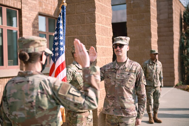 Maj. Meghan Smith, chief of public affairs for the 158th Fighter Wing, Vermont Air National Guard, conducts the oath of enlistment for Tech. Sgt. Richard Mekkri.