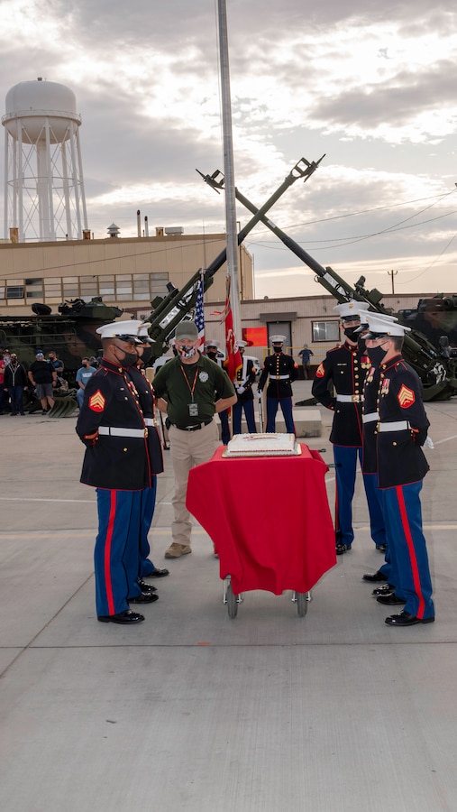 With raised and crossed M777 Howitzer barrels, during the  245th Marine Corps birthday celebration, the oldest Marine, 67-year-old Leland Schnaufer, and the youngest Marine, 21-year-old Cpl. Kyle Westover, stand ready to receive the first slice of cake at Production Plant Barstow, Marine Depot Maintenance Command, aboard the Yermo Annex of Marine Corps Logistics Base Barstow, California, Nov. 6.