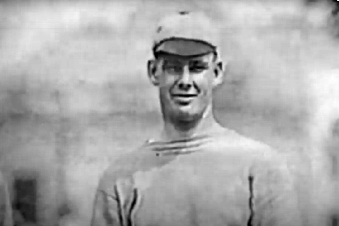 A man in a baseball player’s uniform poses for a photo.