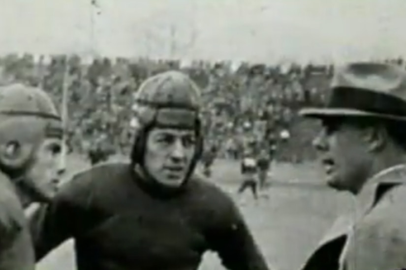 A man talks to football players during a game.