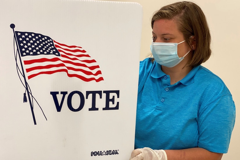 A woman sanitizes a voting station.