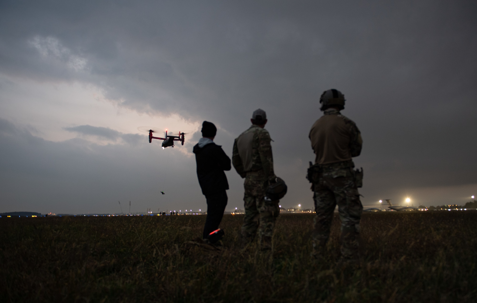 Members with the 320th Special Tactics Squadron and Charlie Company, 1st Battalion, 1st Special Forces Group (Airborne) watch as their teammates are hoisted into a CV-22 Osprey