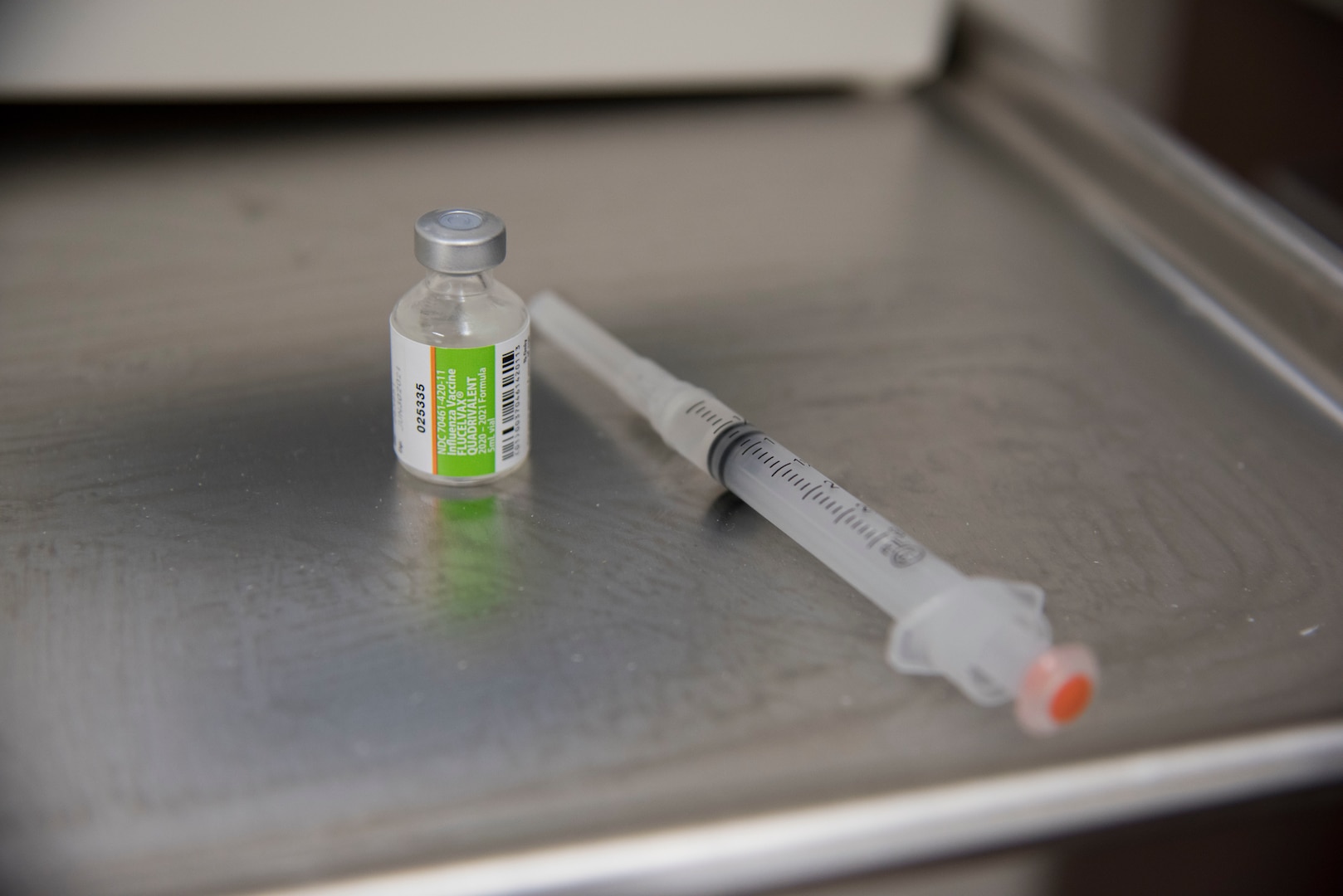 An influenza vaccine sits with a syringe on a medical tray