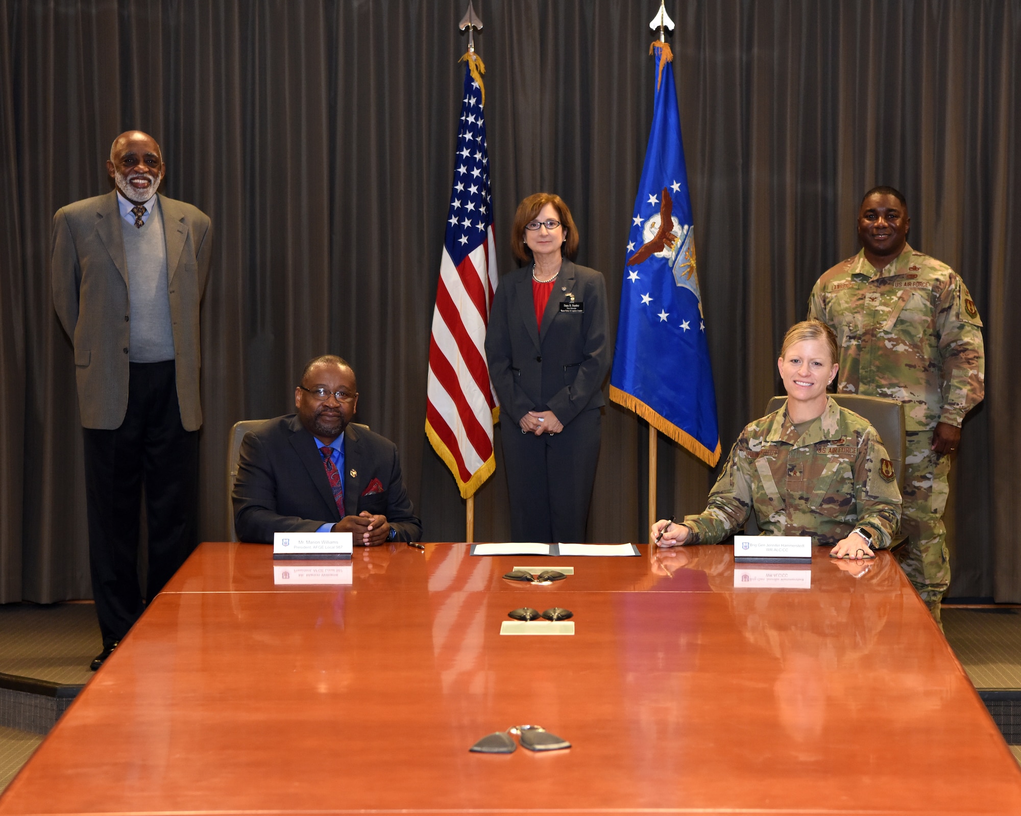 Photo shows five people arranged around a table with the charter placed between them.