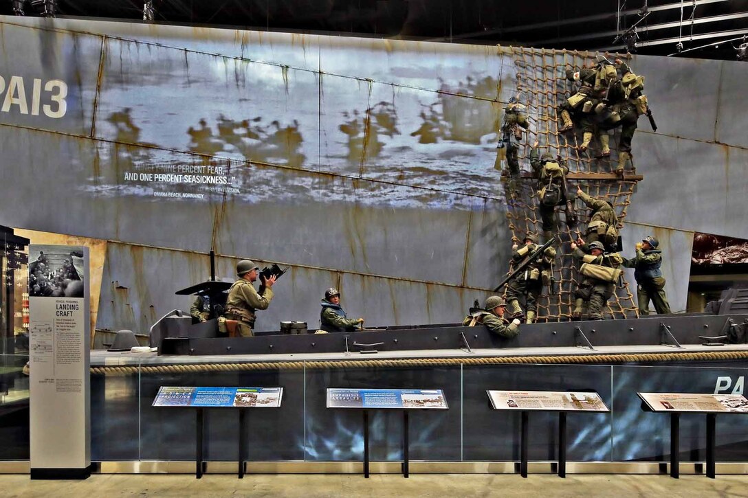 Mannequins in combat uniforms climb down a mesh net attached to a wall.
