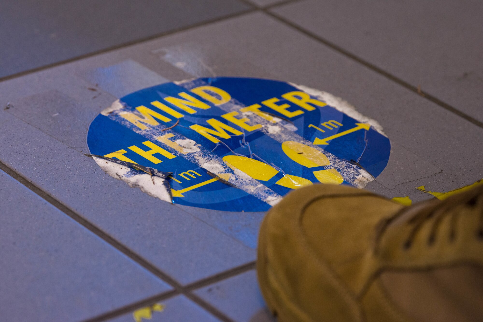 An Airman stands in front of a physical distancing marker in the Northside Post Office at Ramstein Air Base.