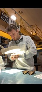 Kyle Hakun, a mechanical engineer at the Naval Sea Warfare Center, Philadelphia Division (NSWCPD), uses a magnification lens to examine a turbine blade. Hakun’s work recently saved the Navy over $380,000. (U.S. Navy Photo by Kyle Hakun/Released)