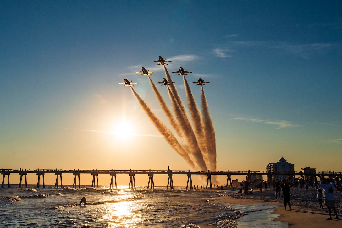 Aircraft fly over a crowed beach.