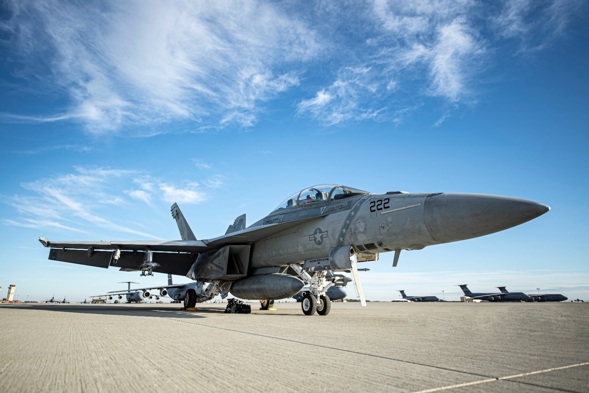 A fighter jet is parked on the flight line. It's mid-afternoon and the sky is clear.