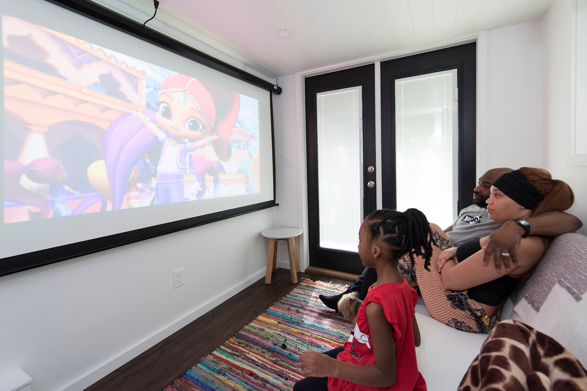 As their 5-year-old daughter enjoys cartoons on their big screen, her parents, Staff Sgt. Kevin and Shanice Inniss relax on the couch in their 400-square-foot "Tiny Home."  Said Inniss, "As important as it was for us to find a place of our own that we could afford, it was equally important for us to be debt-free while pursuing this goal.” The couple is currently stationed at Patrick AFB, Fla., but has orders to relocate to Germany at the end of the year.  (U.S. Air Force photo by Matthew S. Jurgens)