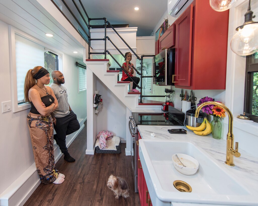 Staff Sgt. Kevin Inniss and his wife, Shanice, along with their dog Quincy, watch as their daughter, Urie, sits proudly on the stairs of the family's newly-constructed Tiny Home.  The Inniss family received a grant from Operation Tiny Home in partnership with Sutter Homes Family Vineyards to build 400-square-feet of living space to call their own. (U.S. Air Force photo by Matthew S. Jurgens)