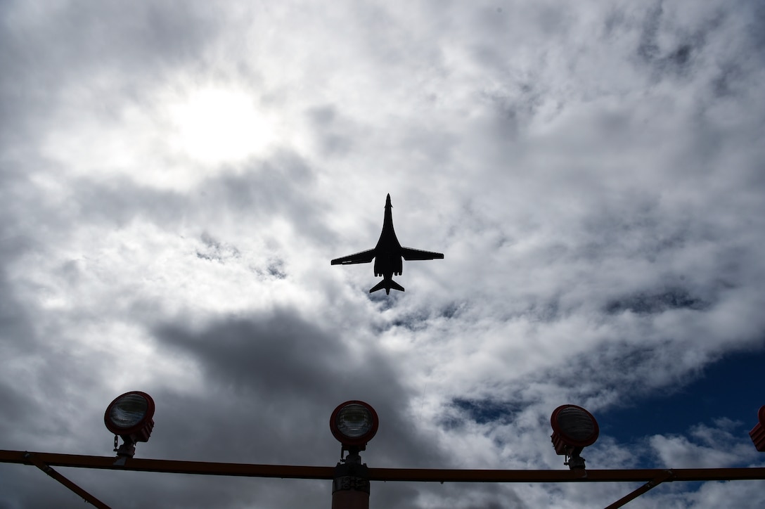 An aircraft flies over a light pole.