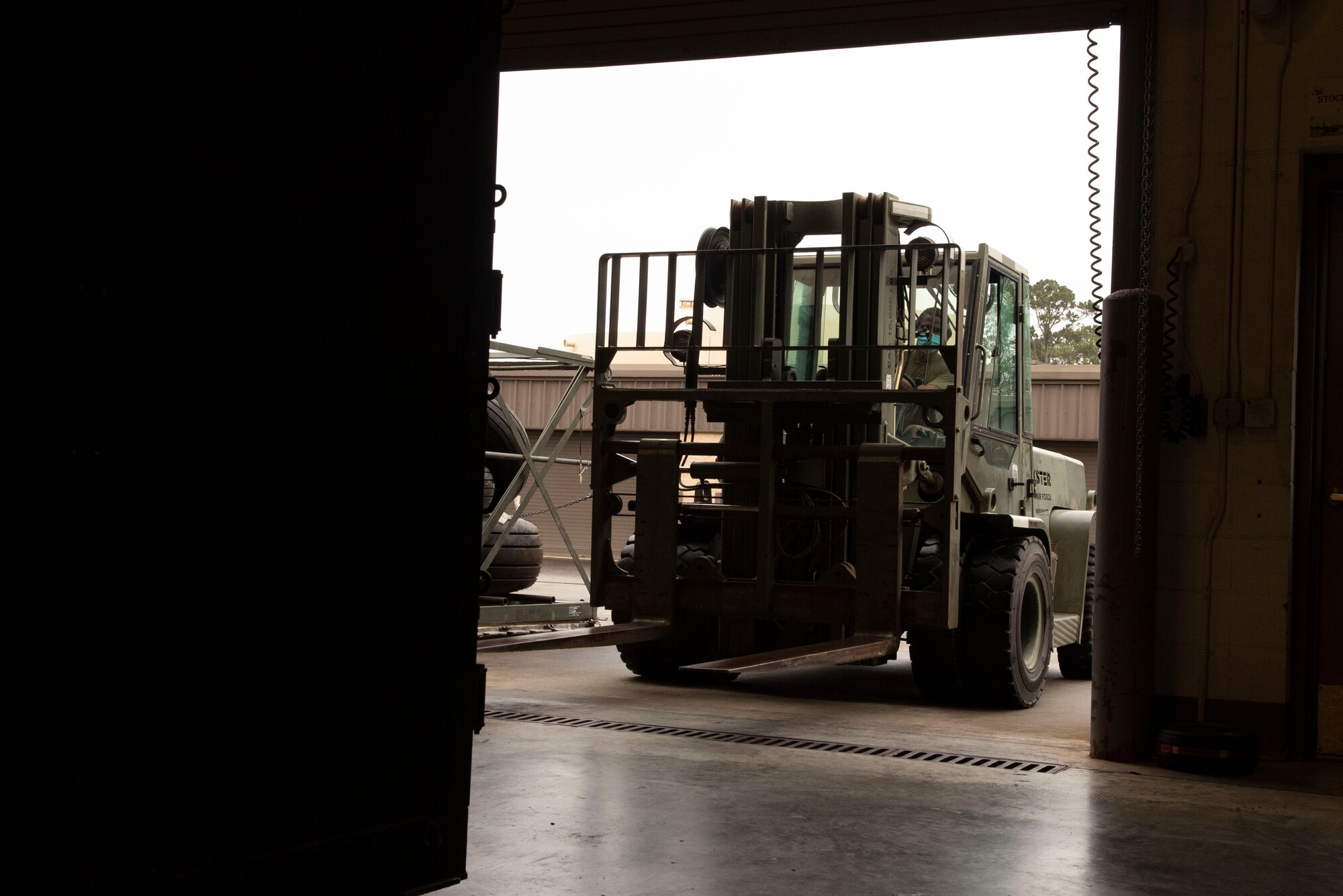 A photo of an Airman picking up a package with a forklift.