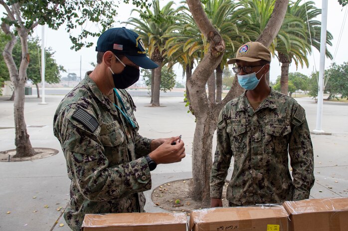 PORT HUENEME, Calif. (Nov. 4, 2020) Lt. Cmdr. Todd Coursey, with Naval Sea Systems Command, issues a proximity tracker to Builder Constructionman Kory Johnson, with Naval Mobile Construction Battalion (NMCB) 5, onboard Naval Base Ventura County, California. The Seabees with NMCB-5 are piloting this innovative technology to help the Navy streamline COVID-19 contact tracing efforts. NMCB-5 is homeported in Port Hueneme, training for an upcoming deployment in the Indo-Pacific region to support U.S. and partner nations through high-quality construction and combat engineering.