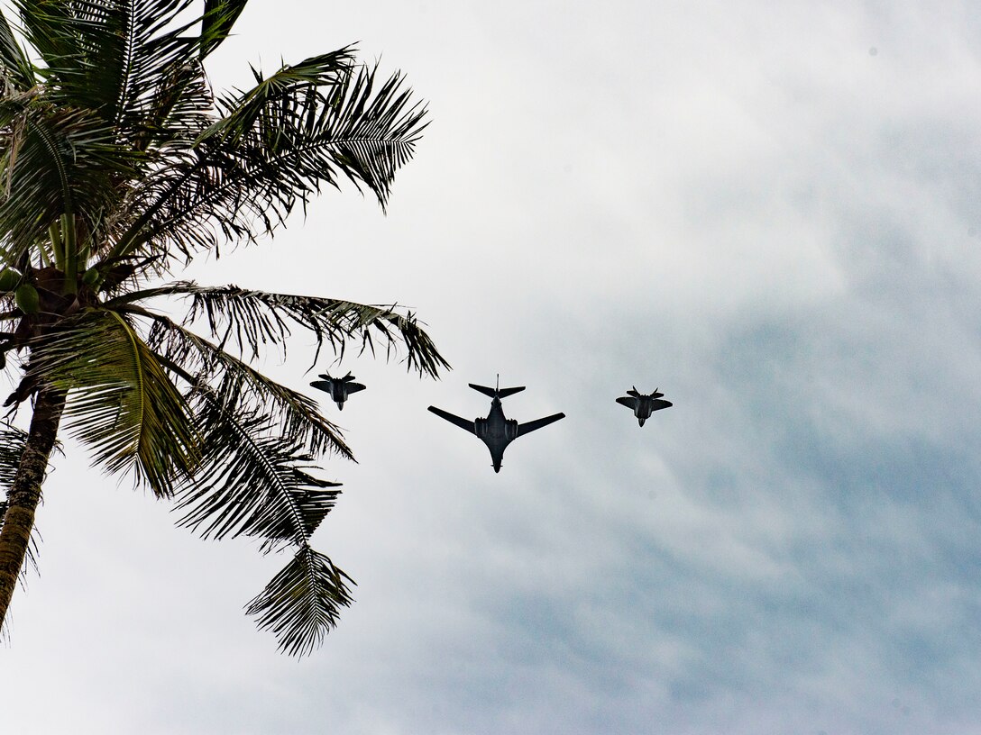 A B-1 Lancer, center, and two F-22 Raptors fly in formation to commemorate Veterans Day over Asan Beach Park, Guam, Nov. 11, 2020. The B-1 Lancer is based out of the 9th Bomb Squadron at Dyess Air Force Base, Texas, and the F-22 Raptors are based out of the 94th Fighter Squadron at Joint Base Langley-Eustis, Virginia.  (U.S. Air Force photo by Alana Chargualaf)