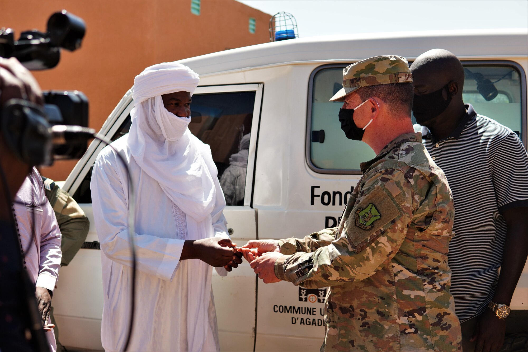 U.S. Air Force Lt. Col. Jeffrey Gipson, 724th Expeditionary Air Base Squadron commander, hands Mayor Mamane Boukari of Agadez City, keys to a fully functional ambulance and life-saving medical equipment at the District Sanitaire Commune d'Agadez clinic in Agadez, Niger, Oct. 30, 2020. Airmen with 724th Logistics Readiness Flight vehicle maintenance worked to repair the ambulance during their off-duty time.